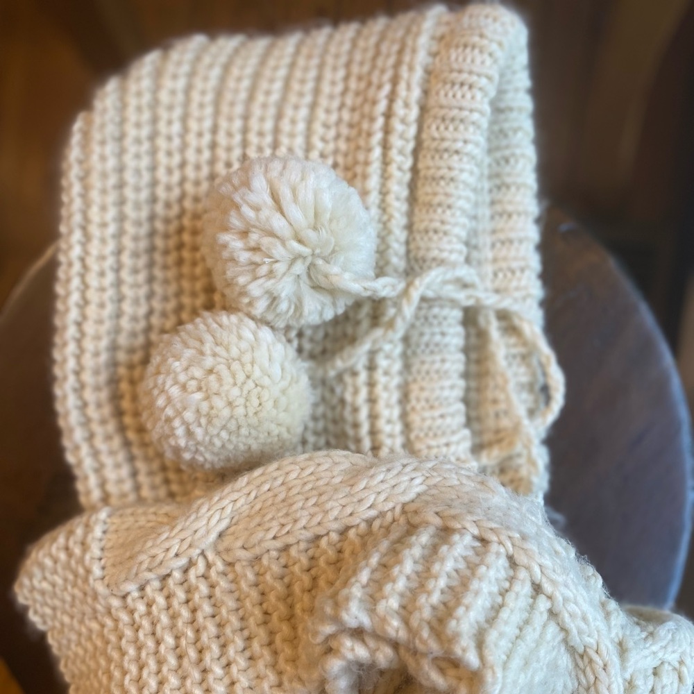 Hooded ivory scarf with ball tassels.